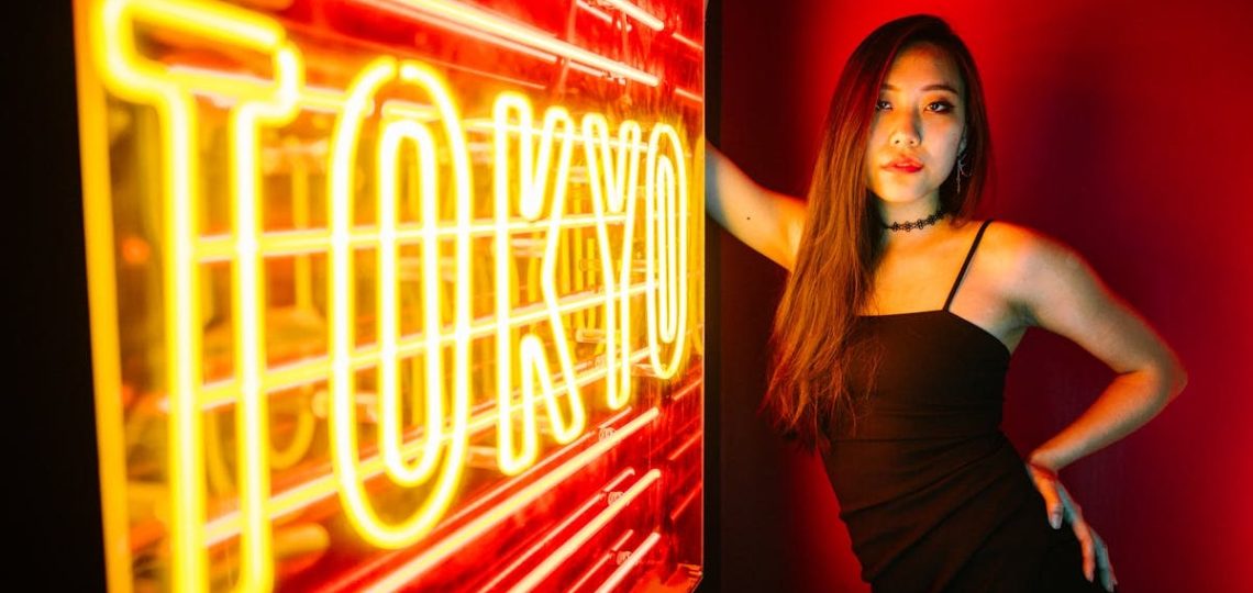 A stylish woman poses by a vibrant Tokyo neon sign, exuding modern urban nightlife.