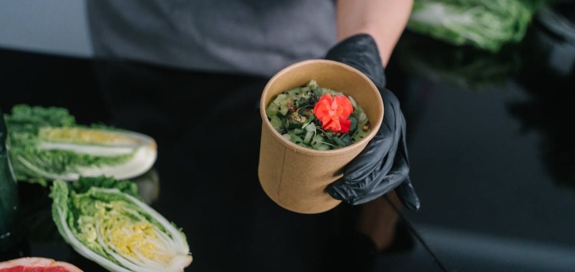 A hand holding a salad bowl with fresh vegetables and a colorful garnish, emphasizing healthy eating.
